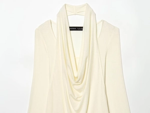 Detail view of cream long sleeve knit top featuring a draped neckline and shoulder cutouts