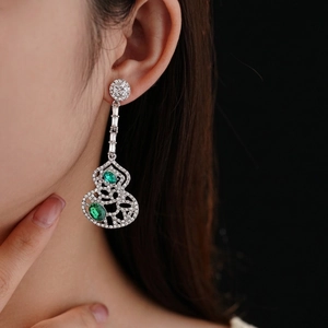 Silver hollow gourd earrings with green gemstones and zircon accents on a female model