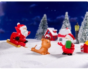 Miniature Christmas resin figurines of Santa and reindeer on artificial snow decor