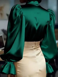 Dettaglio delle maniche a sbuffo e della texture satinata sulla camicia verde scuro