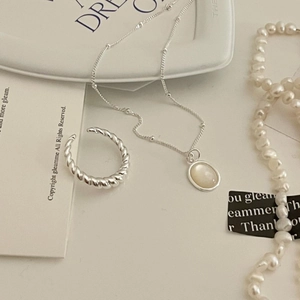 Detailed shot of a 925 sterling silver knot ring and opal necklace on a ceramic tray