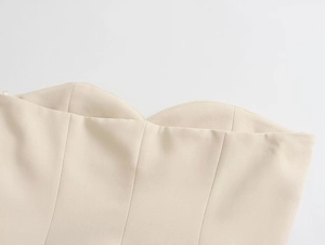 Macro detail of wave-shaped neckline and stitching on beige strapless bodice top