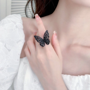Close-up of black hollow butterfly ring with inset zircon stones on a model's finger