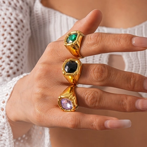Close-up of vintage gold rings featuring green, black, and purple square gemstones