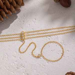 Detail view of 18K gold plated hand chain with white cubic zirconia stones on stone surface