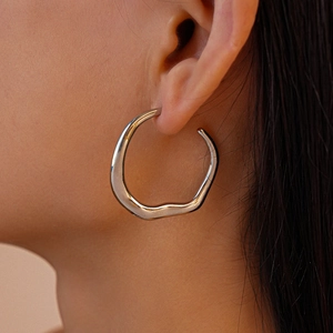 Irregular silver geometric hoop earring with a polished metallic finish on a female model