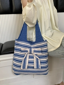 Macro view of blue and white striped knitted tote bag with large decorative bow detail