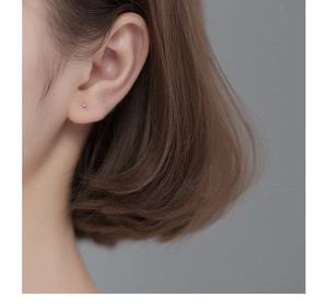 Close-up of a minimalist 999 sterling silver stud earring on a female ear model