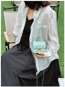 Detail of mint green quilted jelly bag with gold hardware lock and metal chain strap
