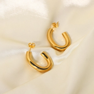Boucles d'oreilles en C en acier doré 18 carats sur fond de tissu en soie beige