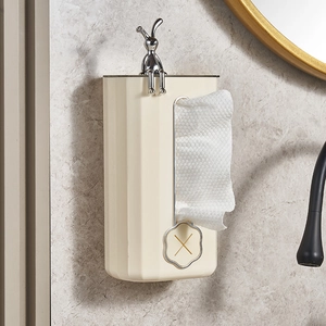 Wall-mounted cream white tissue box with a silver rabbit ornament on marble wall