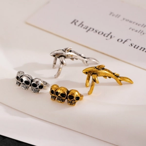 Detail of vintage gothic jewelry featuring shark and skull shapes in gold and silver