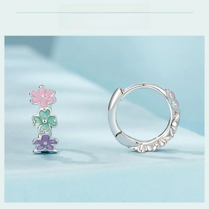 Detailed macro view of colorful enamel flowers on silver hoop earrings for women