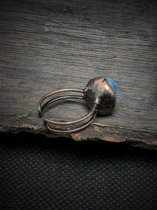 Macro detail of vintage bronze ring with irregular blue crystal on dark wood surface