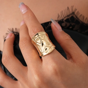 Close-up of wide golden ring with irregular lava texture and molten metal surface