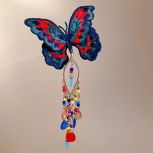 Close-up of butterfly hair clip with blue embroidery and colorful crystal tassels