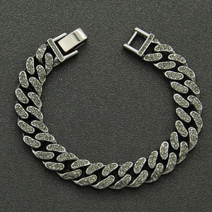 Macro detail of silver hip hop Cuban bracelet with vibrant green crystals and full diamond pavé