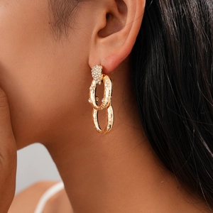Detail of vintage gold chain earrings with rhinestones worn by a model on black hair