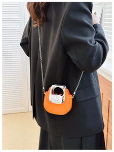 Mini orange crossbody bag with silver chain strap shown on black suit jacket