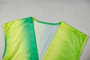Detail of green and yellow gradient satin fabric with V-neck stitching and sleek texture