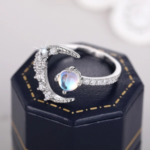 Macro shot of silver crescent moon ring with glowing moonstone on a navy jewelry box