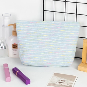 Detail of light blue woven makeup bag featuring colorful striped texture and roomy interior