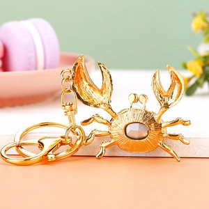 Detail of a golden crab keychain with a large grey gemstone and lobster clasp
