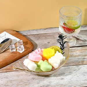 Cute animal-shaped soaps and wax melts in a gold-rimmed leaf glass bowl on a wooden table