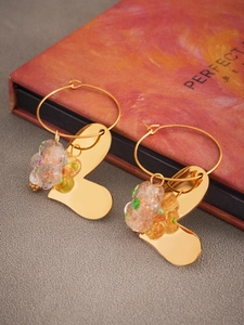 Détail de boucles d'oreilles créoles dorées avec pendentifs cœur et perles fleurs
