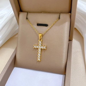 Detailed view of a gold-plated cross pendant with inlaid cubic zirconia in a jewelry box