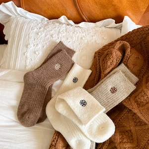 Detail of wool blend thermal socks with floral embroidery in brown and beige tones