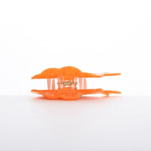 Detail showing an orange translucent acetate butterfly hair claw with a visible metal spring