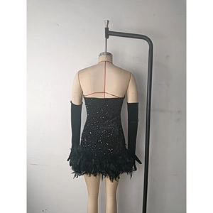 Close-up of black sequined tube dress with feather hem and matching long sleeves