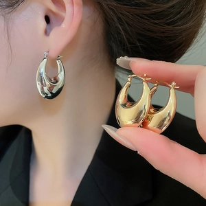 Macro view of teardrop hoop earrings in polished gold and silver metallic finishes