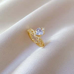 Macro shot of gold crown ring featuring a heart-shaped zircon on champagne silk fabric
