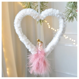 Close-up of plush Christmas fairy ornament with pink feathers hanging on a pine tree