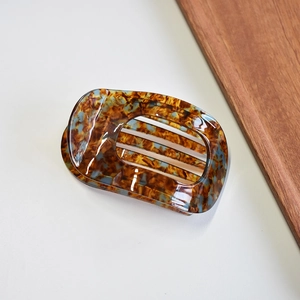 Detail of a large acetate hair claw clip featuring brown and blue tortoiseshell pattern
