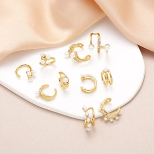 Elegant gold pearl ear cuff set with zircon on white ceramic plate and silk fabric