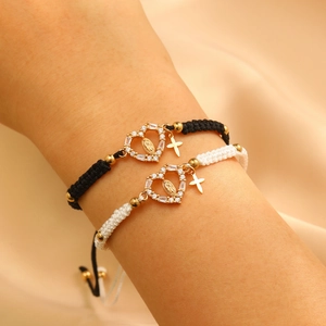 Close-up of black and white woven religious bracelets with Virgin Mary charms on silk