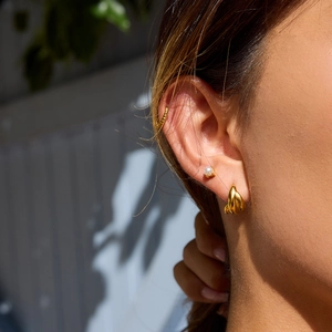Close-up of 18K gold stainless steel triple-layered earring set with pearl on ear