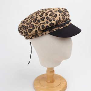 Detail of leopard print baker boy hat with black visor and decorative rope with gold buttons
