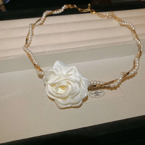 Détail du collier vintage avec rose en satin blanc et fine chaîne métal perle