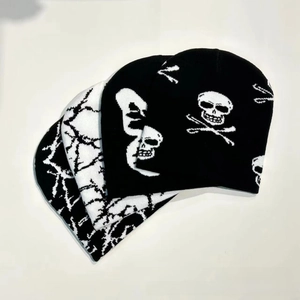 Detail of black and white knitted beanies with skull and branch patterns in a layered view
