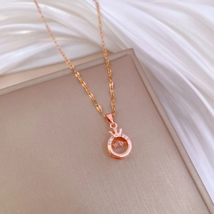 Elegant rose gold crown necklace with dancing pink gemstone on silk fabric surface