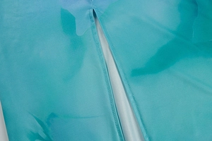 Detailed close-up of side slit and hem stitching on blue-green gradient satin dress