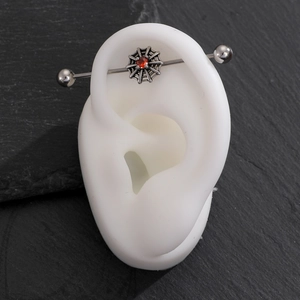 Industrial barbell earring featuring a silver spider web design with a red gemstone center