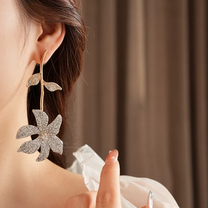 Detailed view of elegant gold floral earrings with crystal rhinestones on a female model
