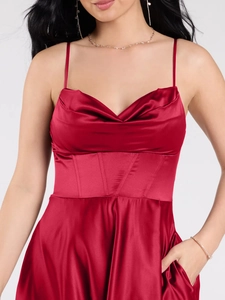 Detail of red satin dress featuring corseted waist and pleated sweetheart neckline