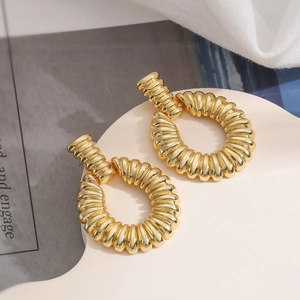 Minimalist 18K gold plated spiral round earrings on an elegant cream display tray