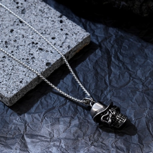 Pendentif tête de mort argenté avec haut-de-forme noir sur une chaîne à mailles carrées